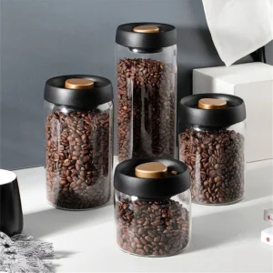 Vacuum sealed coffee canister set - 4 glass sizes with black gold vacuum lids holding coffee beans on kitchen counter