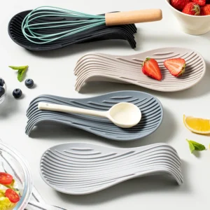 Silicone spoon rest in matte black holding a hot soup ladle beside a pot on a kitchen countertop